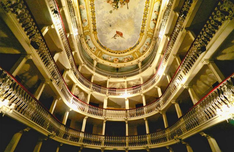 The image shows a spooky place in Portugal. There a theatre. A view from the bottom to the top of the galleries. There are four galleries. And the ceiling painted in fresco.